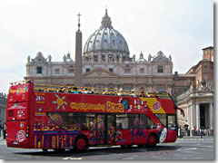 A hop-on/hop-off city sightseeing bus passing St. Peter's and the Vatican in Rome